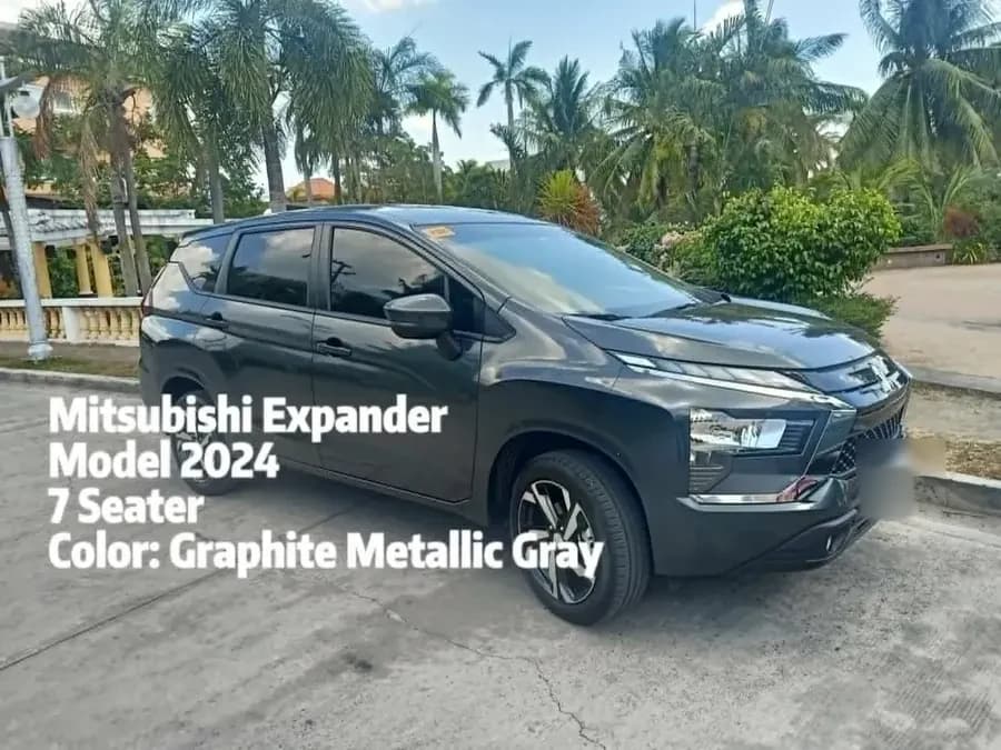 Graphite grey 2024 Mitsubishi Xpander seven-seater parked on a driveway lined with palm trees