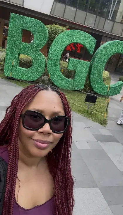 Jessica R photographed in front of the giant green BGC letters in Bonifacio Global City